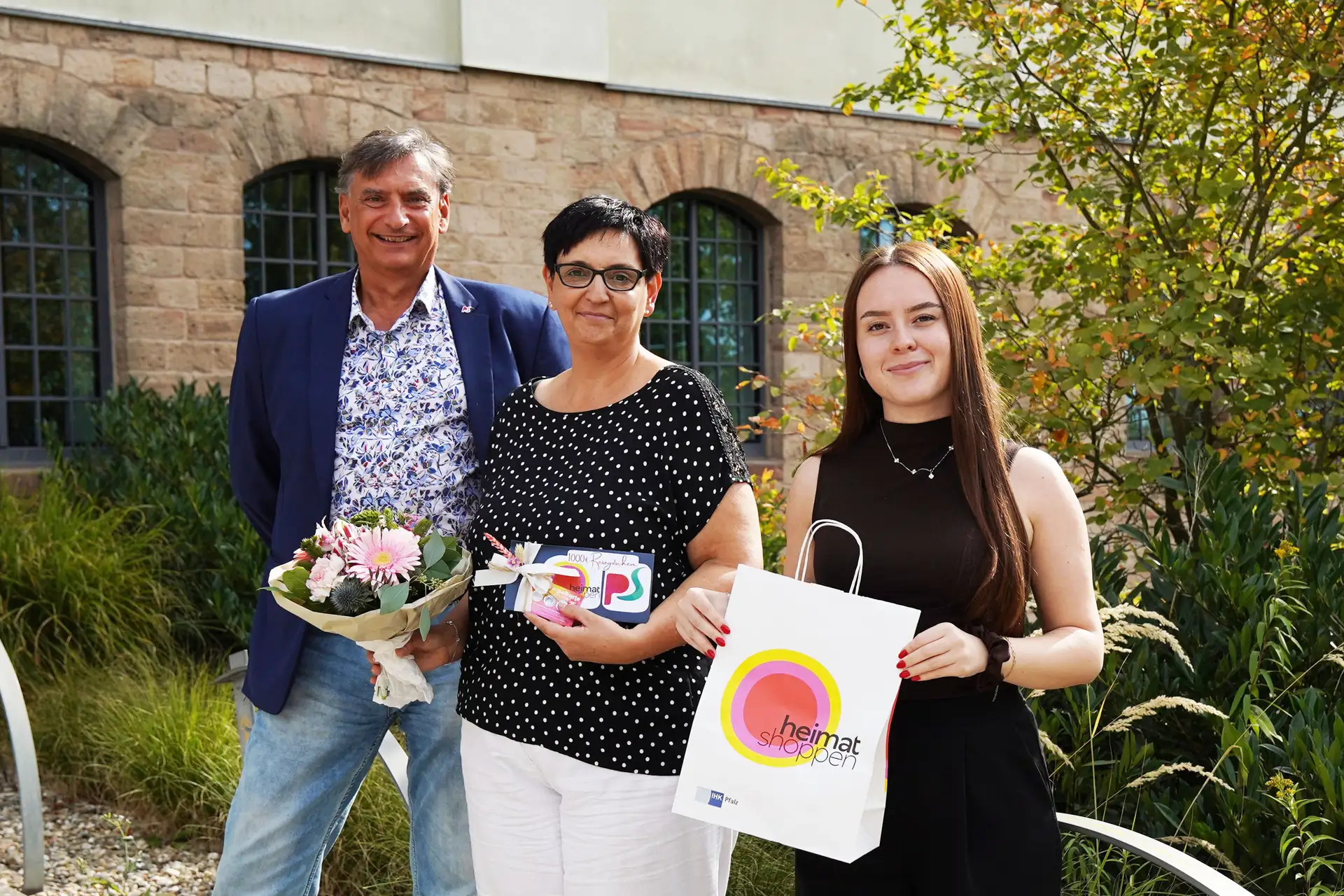 Stadtmarketing-Chef Rolf Schlicher (links) und seine Mitarbeiterin Julia Göttmann (rechts) freuen sich mit Petra Kern (Mitte) über den Gewinn des 1000-Euro-Reisegutscheins der Aktion „Heimat Shoppen“