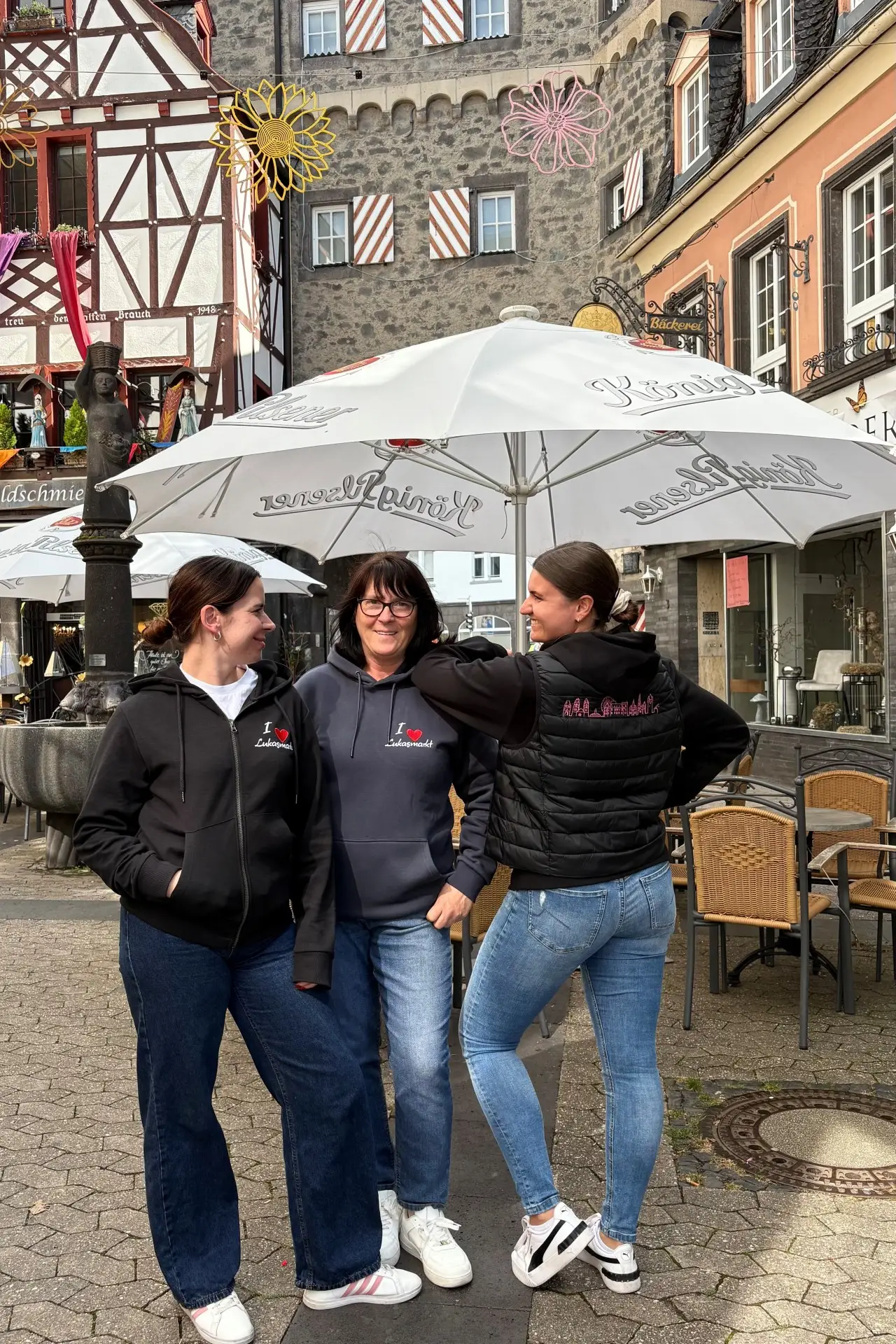 Souvenir- und Merchandising-Artikel zum Lukasmarkt, darunter Bekleidung und Accessoires, auf einer Präsentationsfläche.