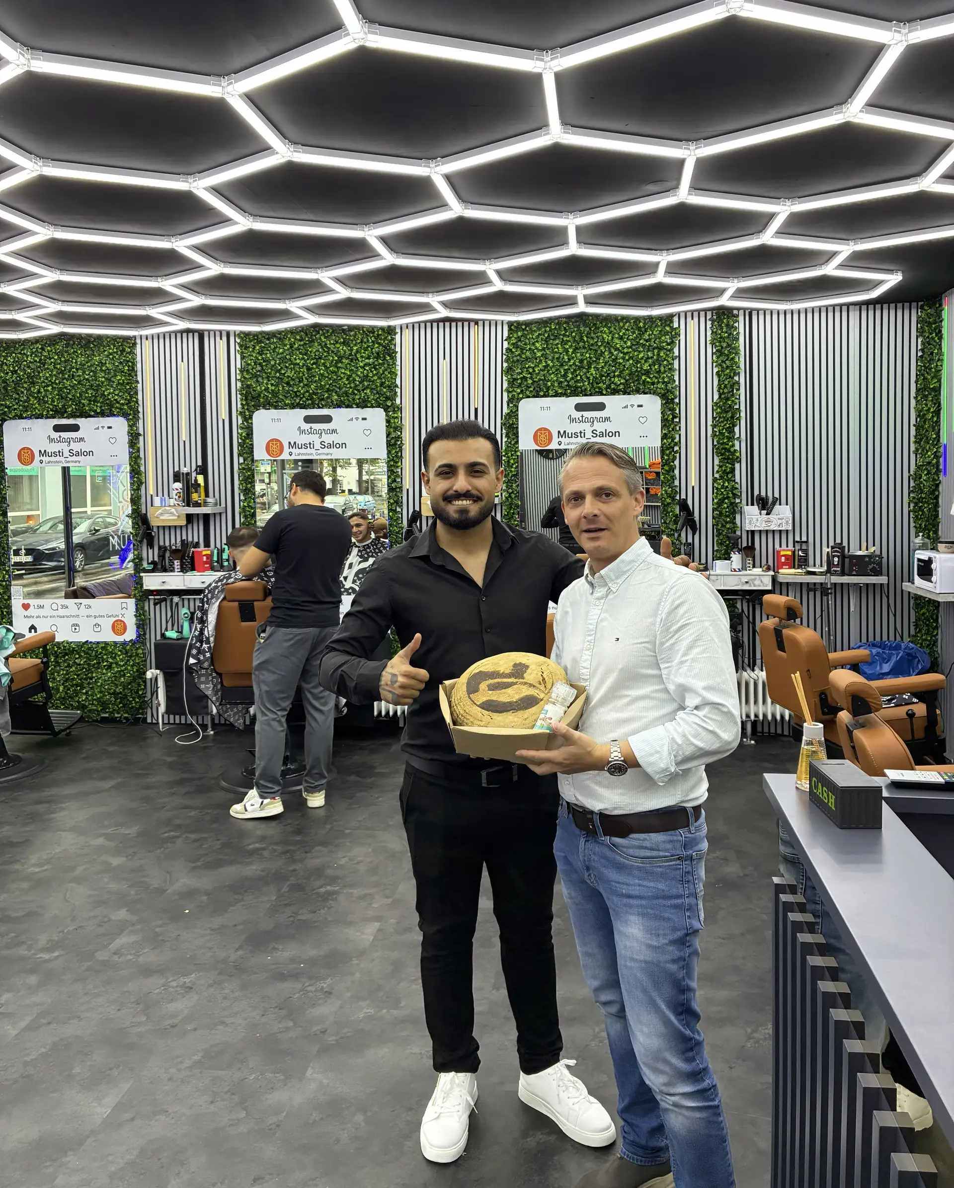 Wirtschaftsförderer Christoph Noack begrüßt Mustafa Jouma in seinem neuen Salon und überreicht ihm traditionell Brot und Salz.